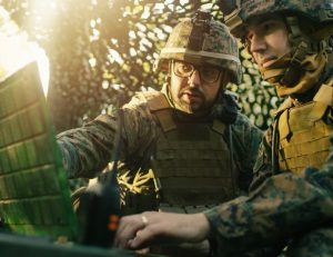 two militray personnel in the field on satcom