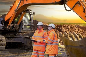 Two men in front of mining equipment